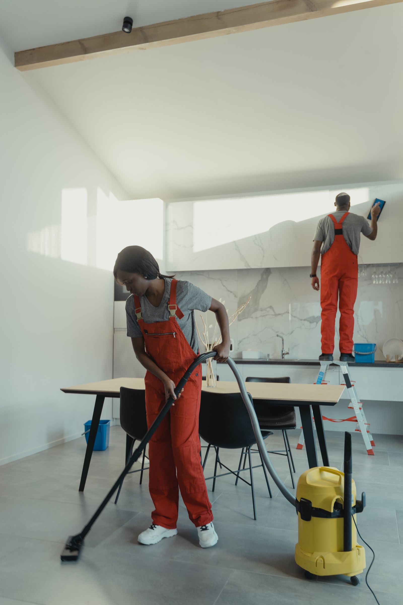 Two professional cleaners working in a bright modern kitchen